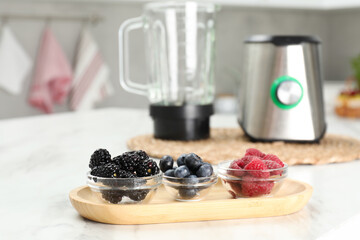 Blender kit and fresh berries on white marble table, selective focus