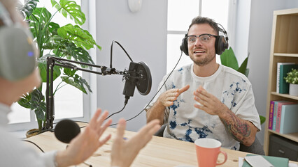 A podcast interview indoors with a man and woman conversing in a studio setup with microphone and headphones.