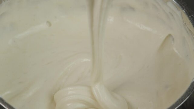 Confectioner whips eggs with sugar and flour in a metal bowl. Cream is whipped to make a biscuit. The concept of making confectionery desserts.