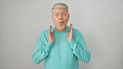Surprised senior man with gray hair in a turquoise sweater gesticulating against a white background.