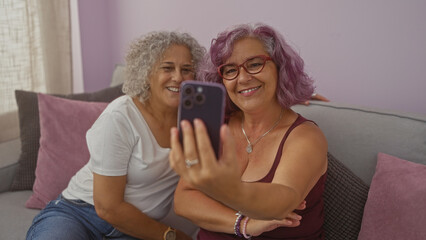 Women taking a selfie together in a cozy living room, showcasing their joyful friendship and smiles in a bright indoor setting