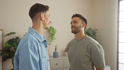 Fototapeta premium Men couple standing together in a cozy living room, showcasing love and connection in a modern home with indoor plants, highlighting an intimate lgbtq family scene.