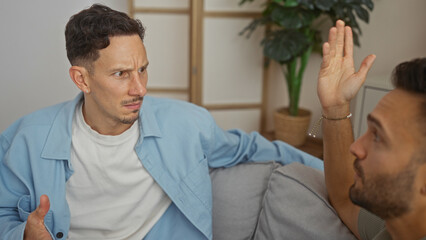Men arguing in a living room focusing on expressions and body language capturing a moment of...