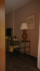 Cozy interior corner with a vintage lamp, framed artwork, woven basket, and minimalist desk set against a warm taupe wall.