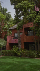 A lush green landscape frames a terracotta villa with balconies, exemplifying serene tropical architecture.