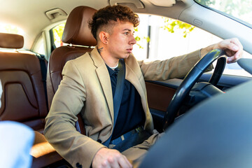 Young businessman in suit driving luxury car