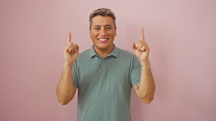 Fototapeta premium Handsome young man smiling over isolated pink background pointing upwards with both hands