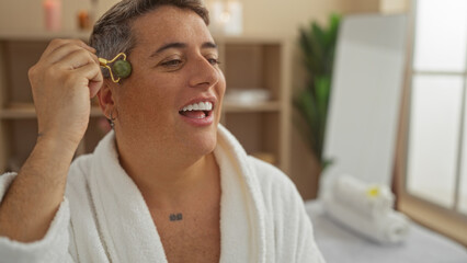 Young man enjoying a wellness treatment in a spa, using a jade roller on his face, wearing a white...