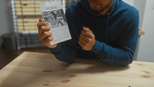 African american man holding a missing person flyer indoors, with a concerned expression and an office scenario in the background.