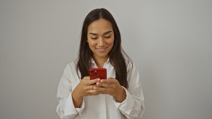 Young woman smiling while using a smartphone indoors featuring a brunette female in casual attire