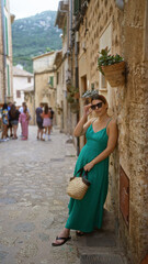 Hispanic woman in green dress relaxing outdoors in the charming streets of valldemossa, mallorca, spain.