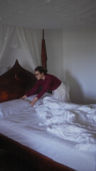 A young hispanic woman meticulously makes her bed in a well-lit bedroom, emphasizing cleanliness...