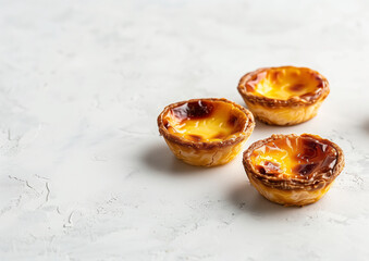 Three Portuguese pastel da nata tarts on the light background with copy space
