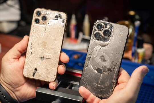 A technician repairs smartphones with broken glass at a phone repair service in the evening