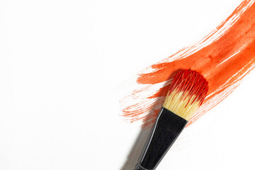 Red paint stroke on a white background with a brush to paint over it