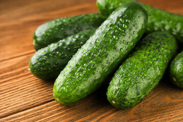 Cucumbers with water droplets close-up on wooden background.