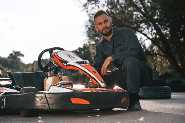 Technician is looking at the vehicle. Man is outdoors, kart racing conception