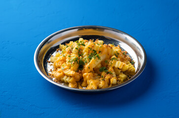 Loaded Cheese Fries with Parmesan and Parsley served in plate isolated on blue background side view of fast food