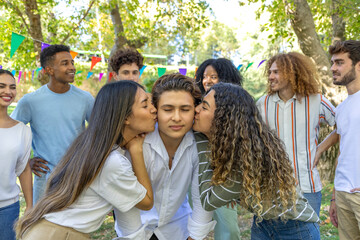 Two young women kissing their friend on the cheek at a party