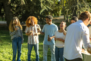 Group of friends having fun and eating sandwiches at a park barbecue party