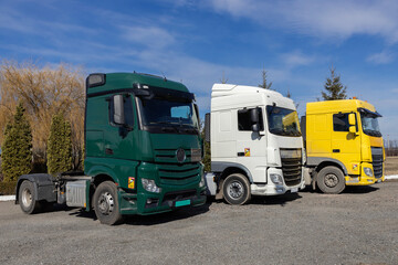 3 trucks parked in a row on a sunny day. cabs of different colors of tractors without trailers. Commercial vehicles, advertising of vehicles for cargo transportation. Industrial machines for leasing