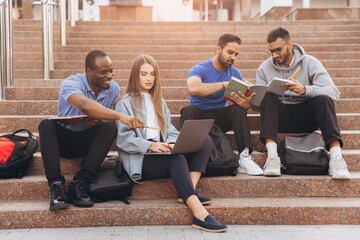 Fototapeta premium Diverse Group of Students Studying Together on University Campus Steps with Laptops and Books