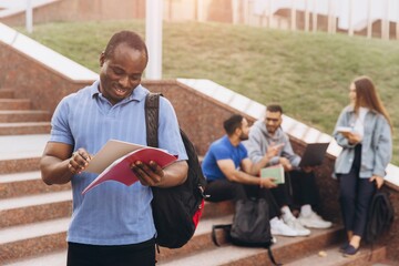 African American Confident Student Holding Books Outdoors with Friends on Campus Steps
