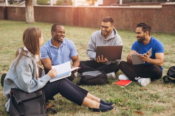 Fototapeta na wymiar Diverse Group of Students Collaborating Outdoors on College Campus Lawn