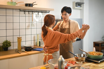 Attractive asian couple dancing in the kitchen. Love, relationship and lifestyle concept