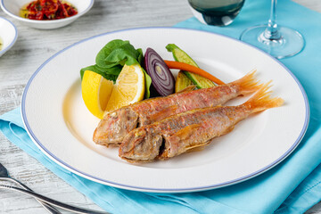 Grilled mullet fish with arugula and mini vegetables on a white porcelain plate