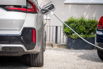 Electric car being charged outside at home in typical British suburban residential setting