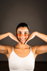 Young woman with perfect glowing skin and natural makeup posing for the camera with medical collagen patches under her eyes to reduce fatigue and puffiness. Skin care.Modern beauty tools concept