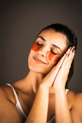 Naklejka premium Young woman with perfect glowing skin and natural makeup posing for the camera with medical collagen patches under her eyes to reduce fatigue and puffiness. Skin care.Modern beauty tools concept