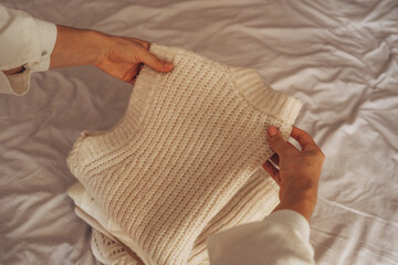 Young Woman Organizing Warm Knitwear on Bed
