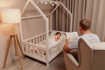 bedtime - young father reading book to his little daughter lying in bed