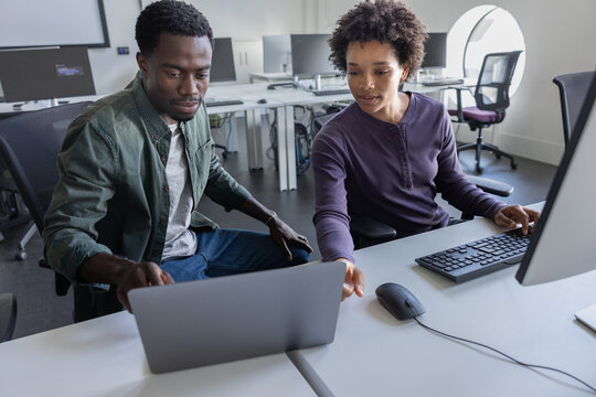 Students discussing computer program in office
