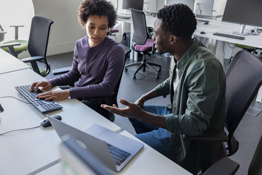 Coworkers discussing computer program in office