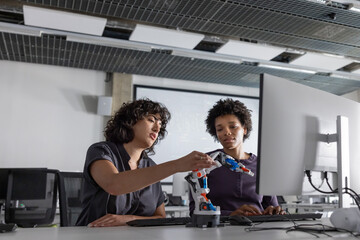 Two female engineers working on a robotic arm