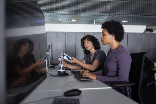 Two female engineers working on a robotic arm