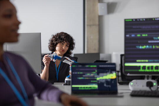 Female engineer working on a robotic arm with coding on computer monitors