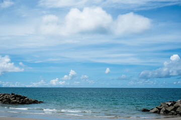 Beautiful nature view soft oceans waves with a deep blue color with clear blue sky and white cloudy background, Stonewall to protect from sea erosion at SAENG CHAN Beach in RAYONG THAILAND