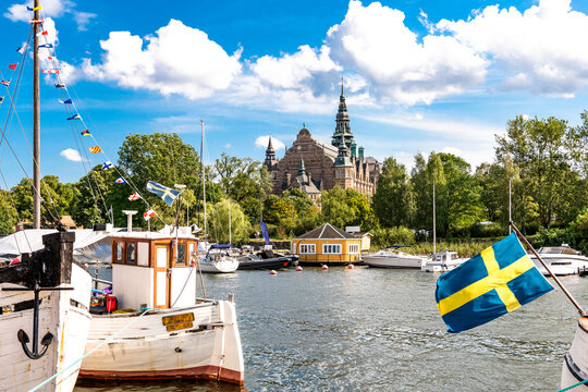 Boats docked in a harbor with the Nordic Museum in Stockholm, Sweden.