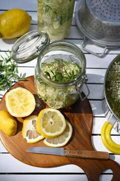 Mason jar with elderflower juice and lemon slices on a breadboard in a summer garden in Hamburg, Germany.