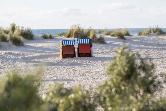 Beach chairs on the sandy shore of the Island of Borkum in Lower Saxony, Germany with a view of the sea and dunes.