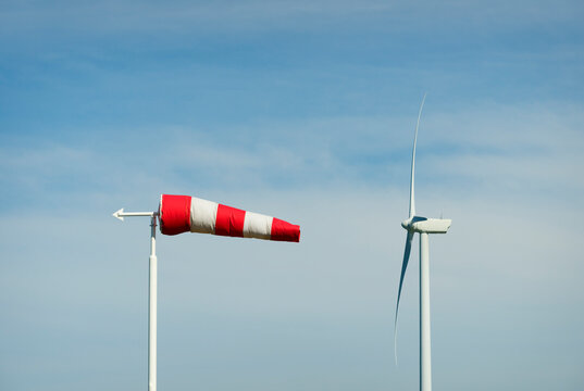 Windsock and wind turbine on a clear day.