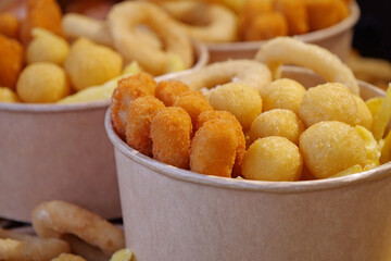 Fried potatoes, cheese fried balls and other baked goods in large paper bowls