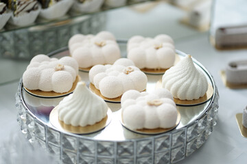 Sweet cakes on a glass stand on a buffet table.