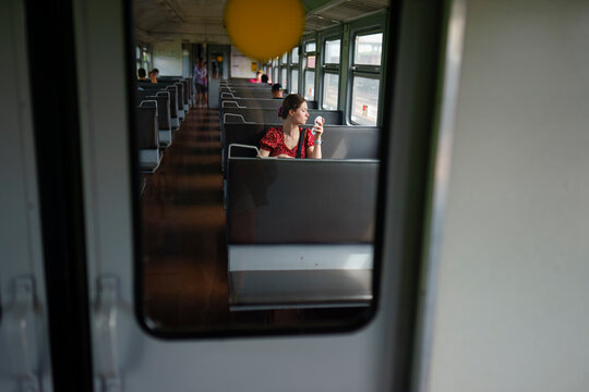 Girl rides on the train and puts on makeup, sitting in the train carriage.