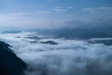 A breathtaking panoramic view of a sea of clouds below a crescent moon and a starry night sky. The silhouette of distant mountains adds depth and drama to this serene landscape. Xindian, Taiwan.