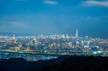 Fototapeta premium A breathtaking panoramic view of a bustling city at sunset. Soft, fluffy clouds drift across the sky, casting a warm glow over the urban landscape. Captured in Dading Mountain, Shulin, Taiwan.